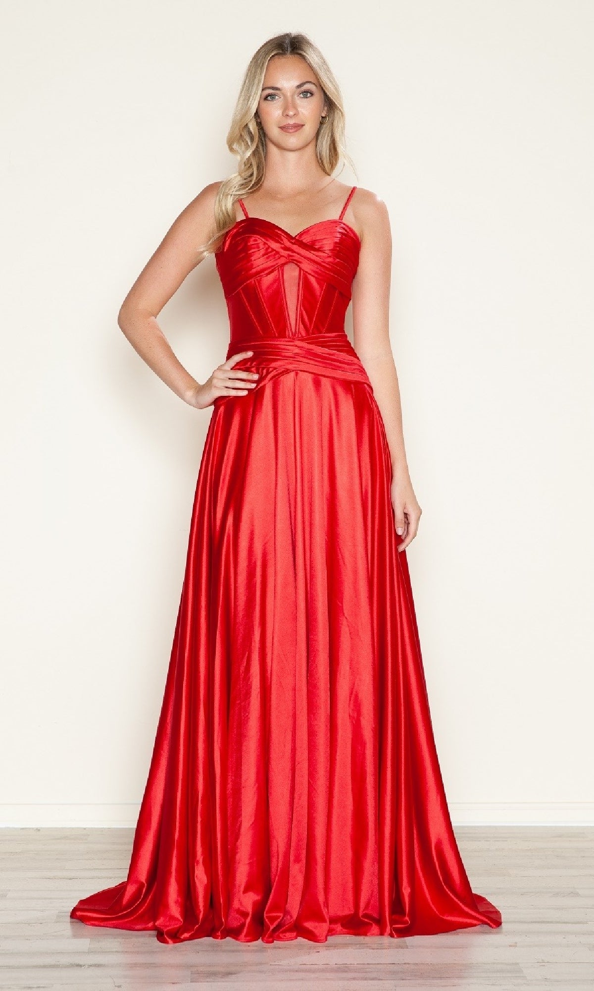 Woman wearing the Cut-Out Long A-Line Prom Dress: Poly USA 9700, a shiny red satin gown with thin straps, fitted bodice, and flowing skirt, stands against a plain light background.